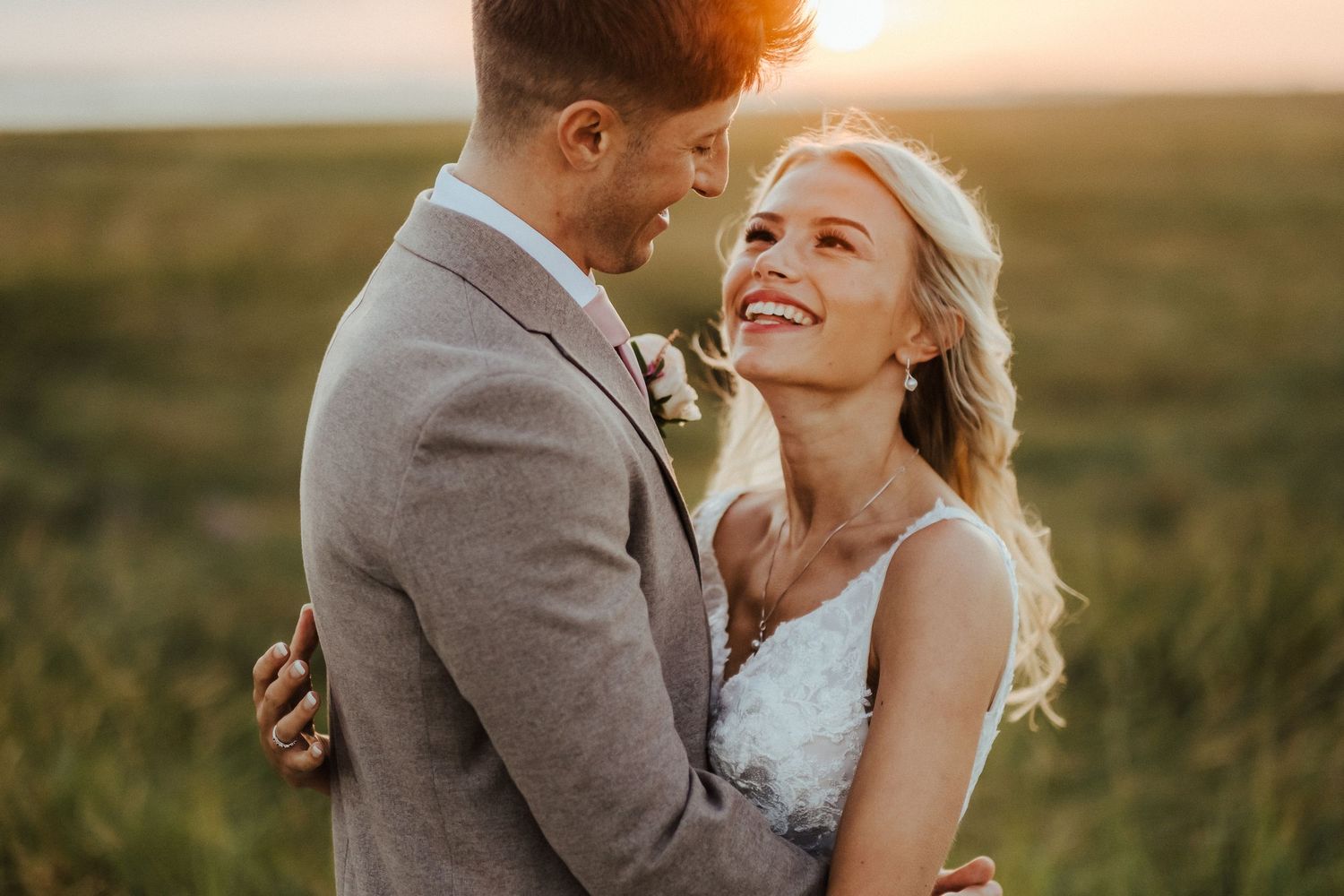 A romantic sunset moment between newlyweds in a golden field.
