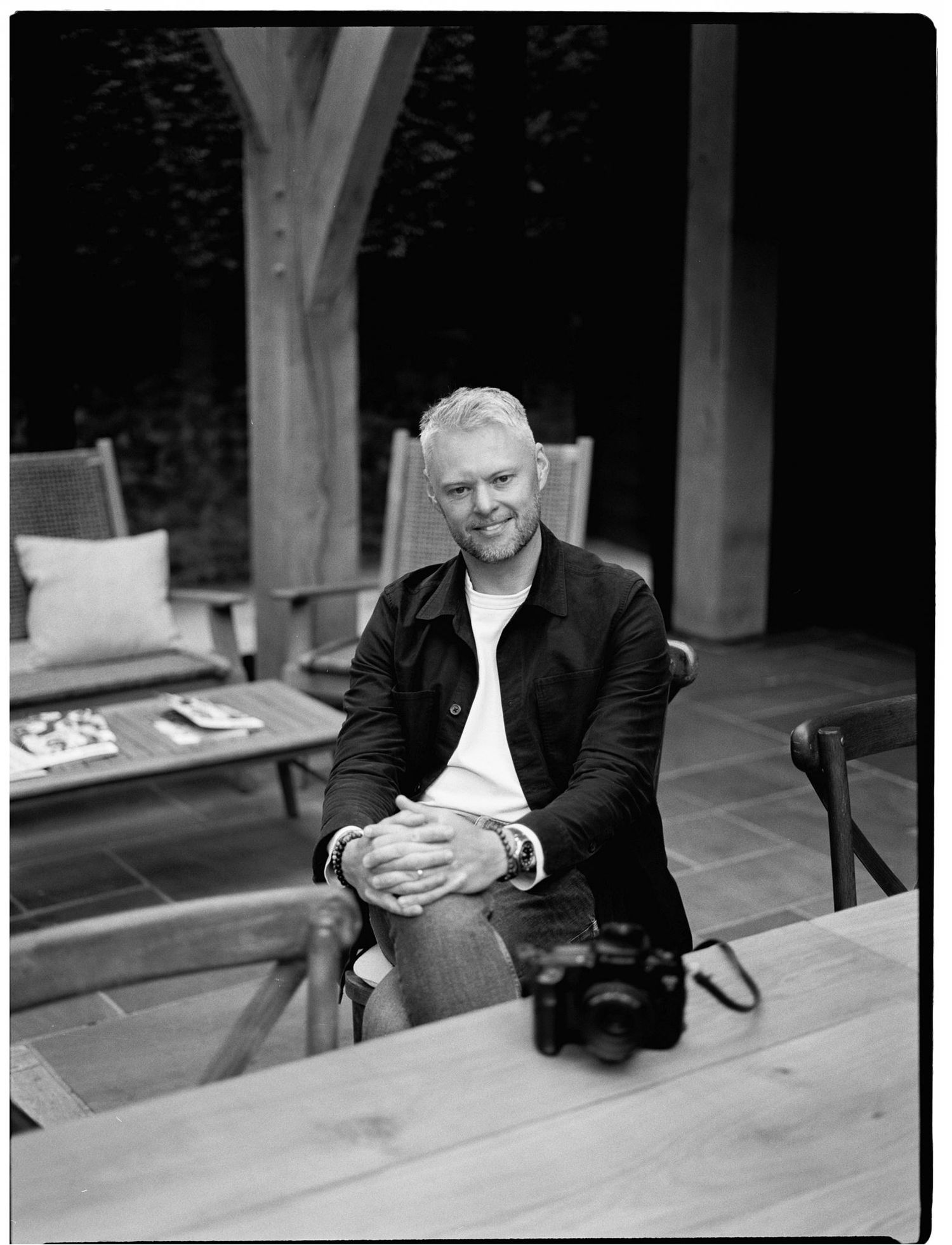 Black and white portrait of Matt Ebbage, London wedding photographer, sitting at a wooden table, shot on film