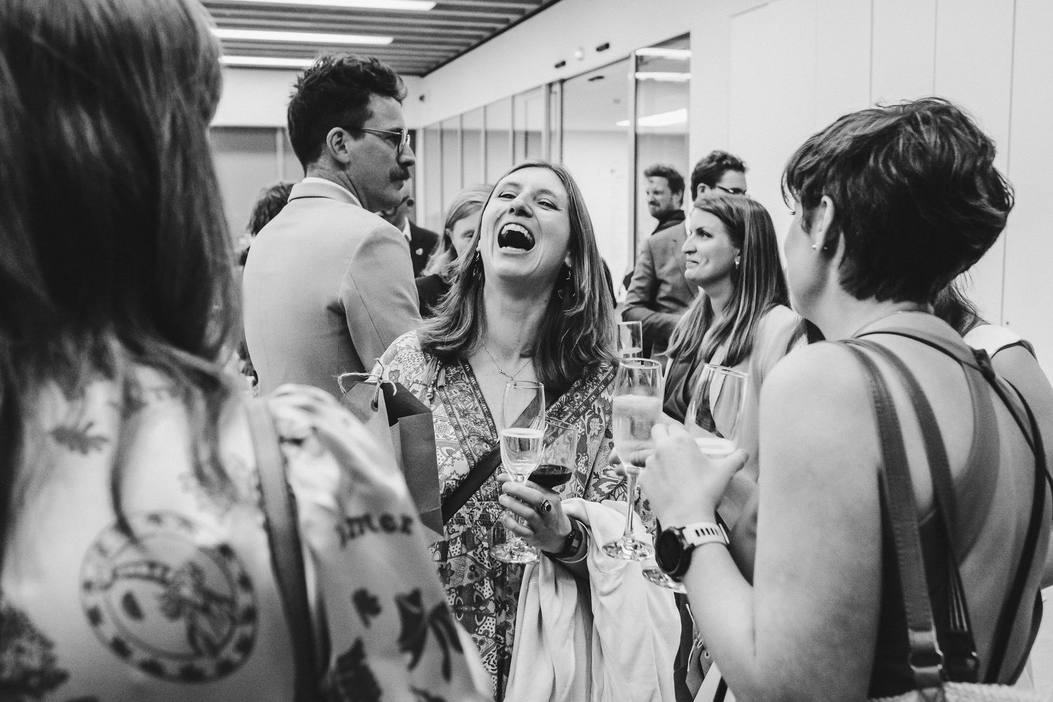 A candid black and white photo shows joyous laughter during a wedding celebration.