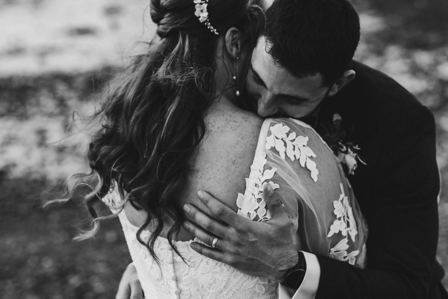 Black and white portrait of a tender moment between newlyweds showing intricate lace dress details.