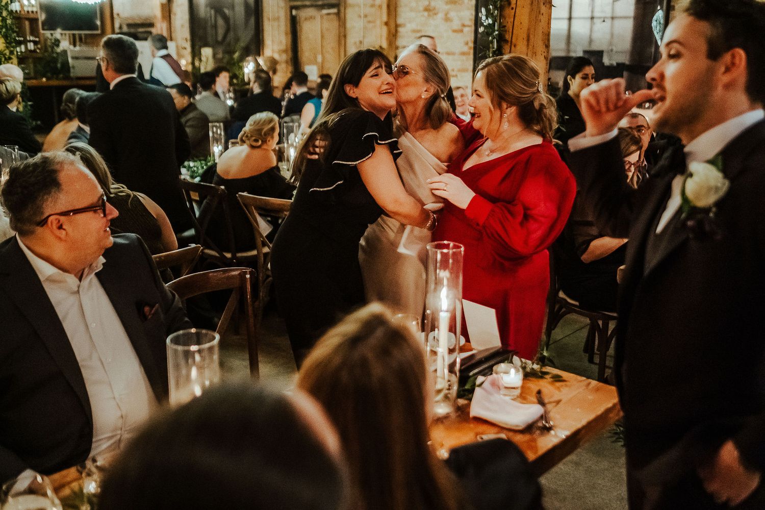 A lively wedding reception scene shows guests dining and celebrating in an intimate restaurant setting.