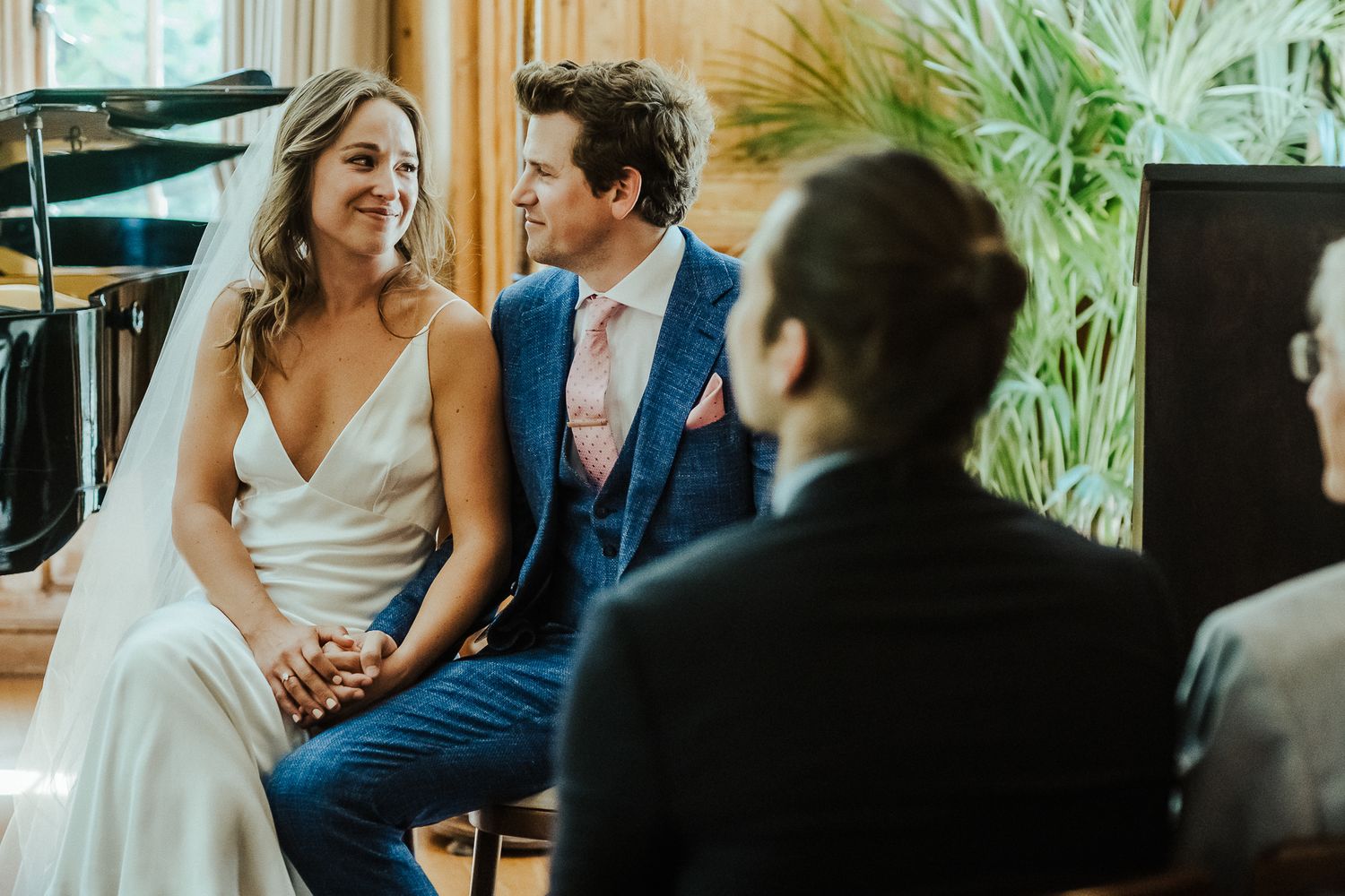 Candid moment during wedding ceremony in bright sunlit room with plants.