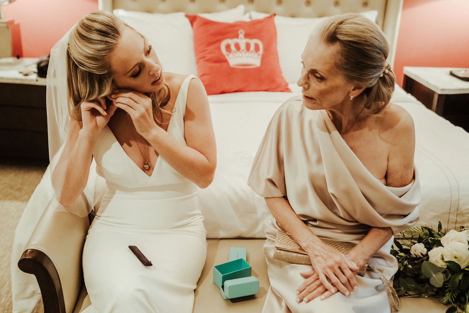 Emotional moment shared between two women on couch with decorative crown pillows.