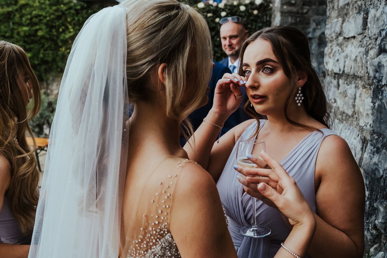 A bridesmaid helps with final touch-ups during an outdoor wedding preparation.