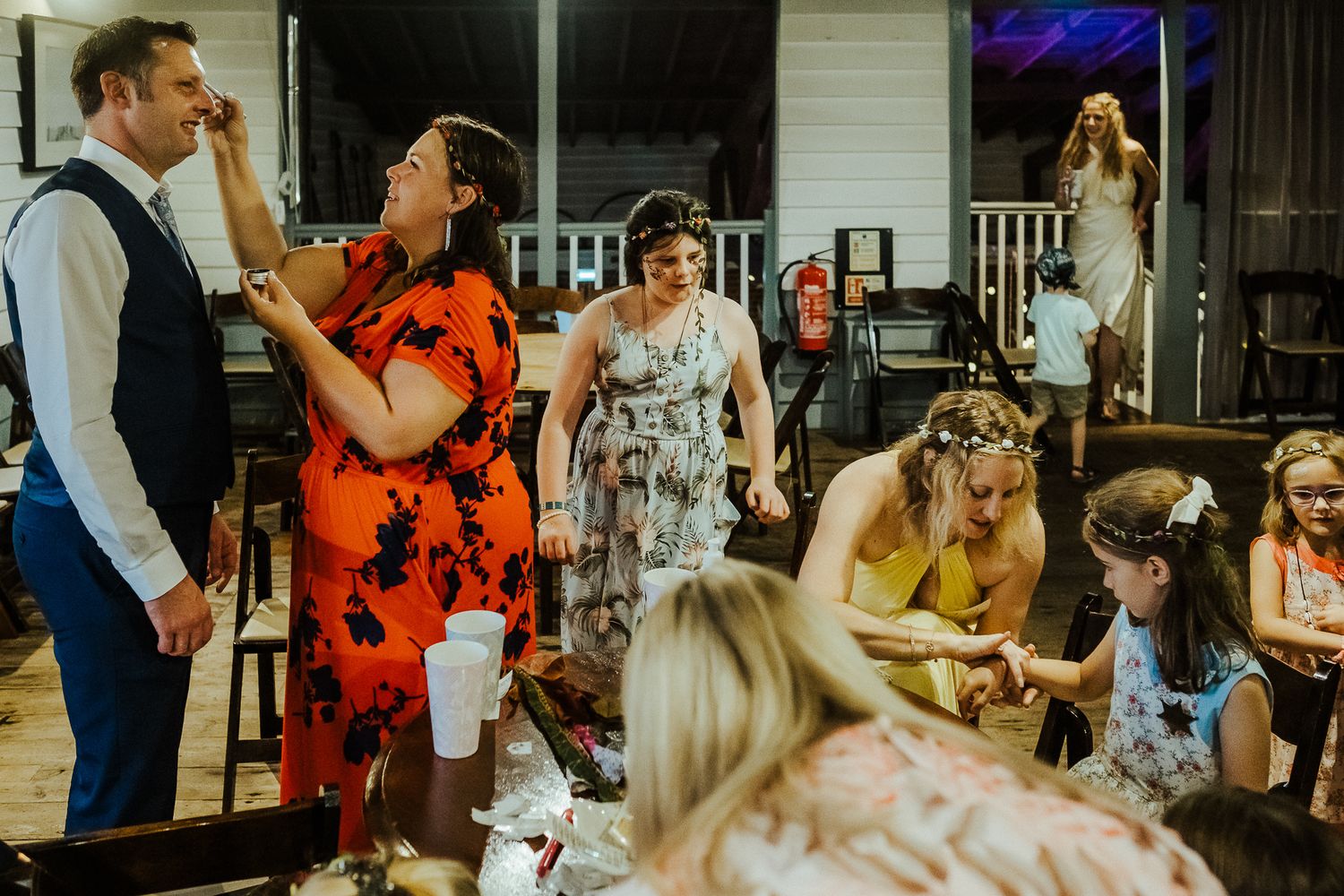 Wedding reception celebration with guests dining and dancing in a rustic venue.