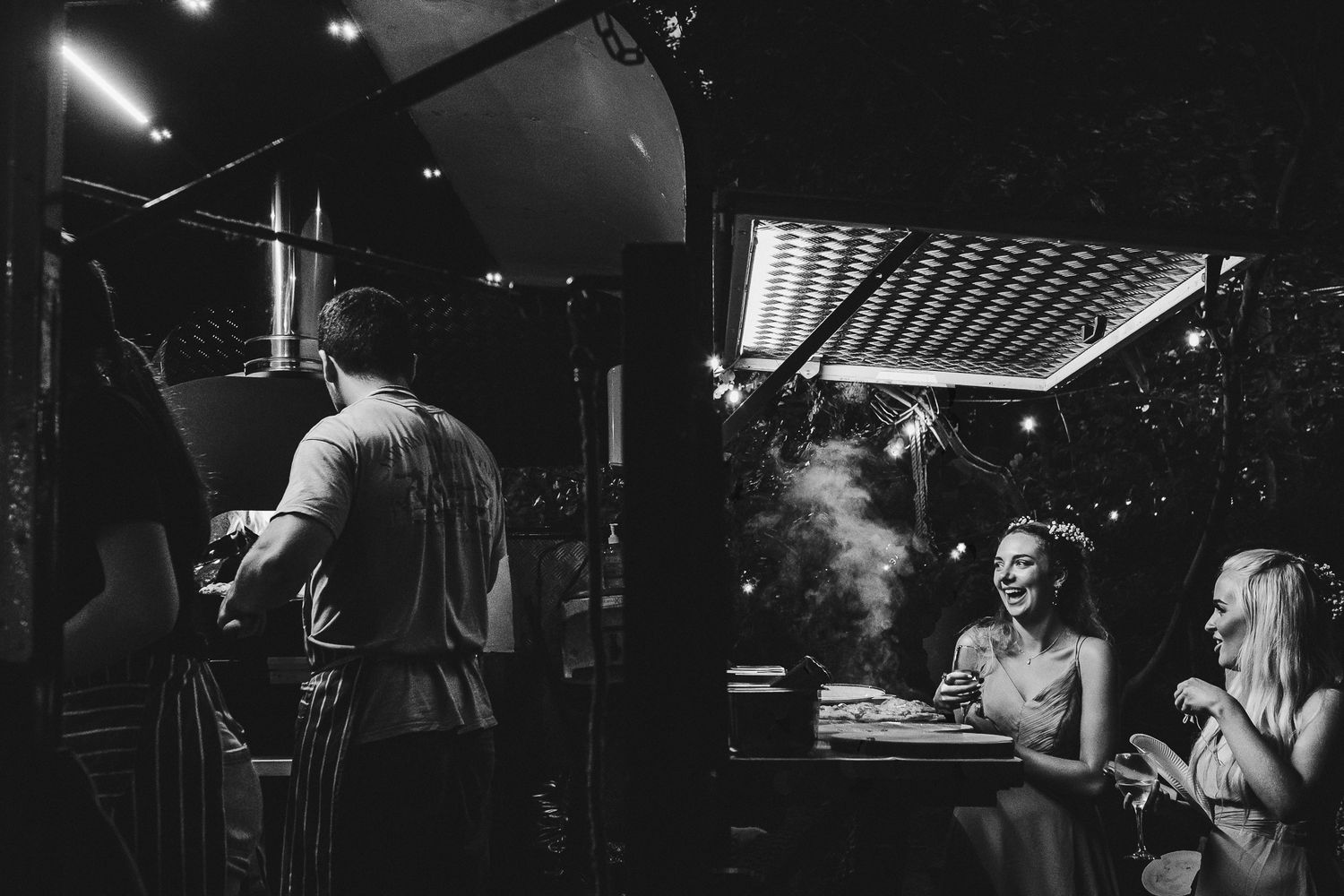Dark and moody reception venue with dramatic lighting and dancing silhouettes.