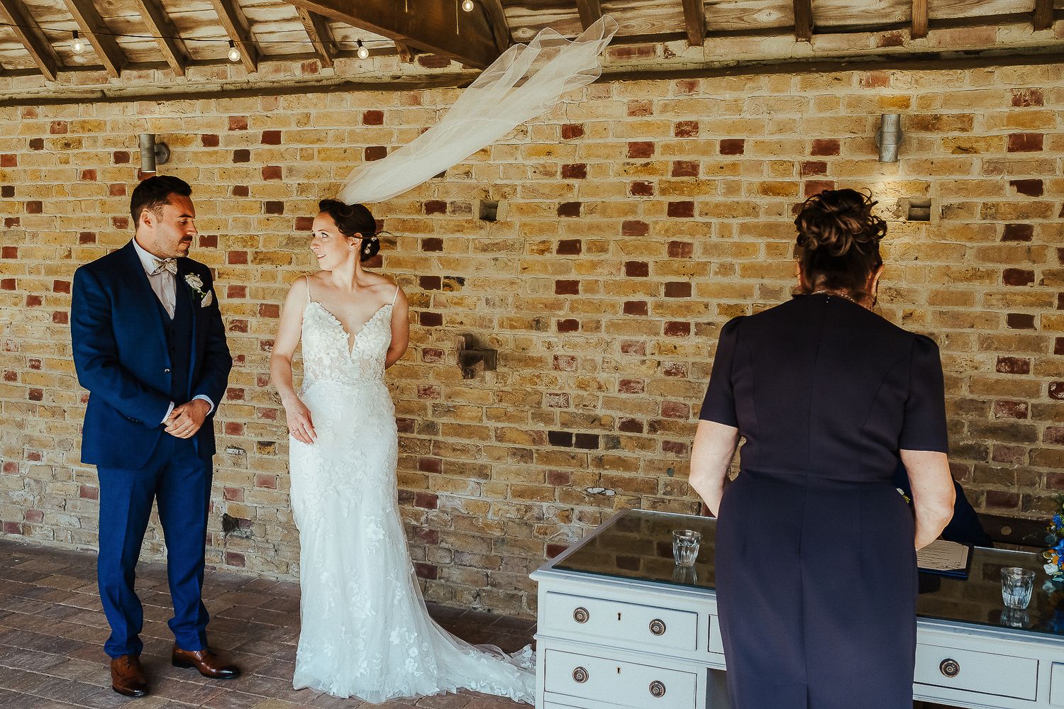 Wedding ceremony preparation in rustic brick venue with bride in elegant lace gown.