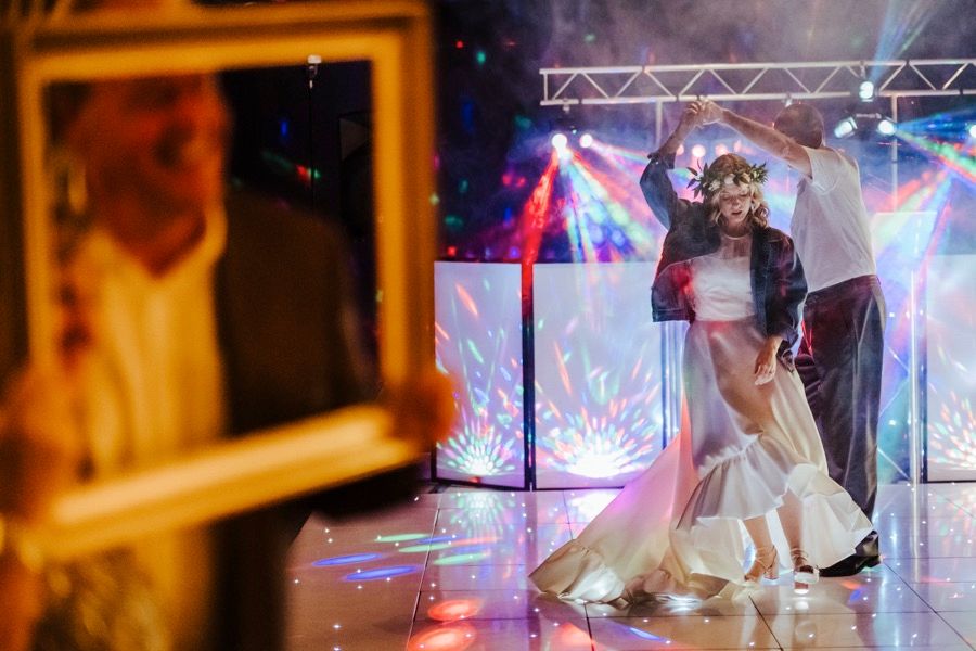 Wedding reception dance floor with colorful lighting effects and dancing silhouettes.