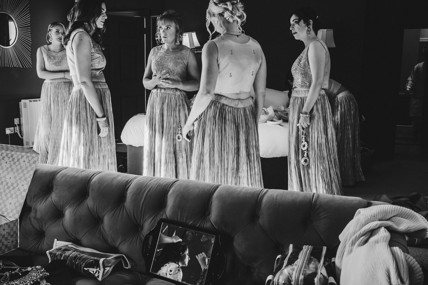 Vintage black and white photo showing people in light flowing dresses gathered around an elegant tufted sofa.