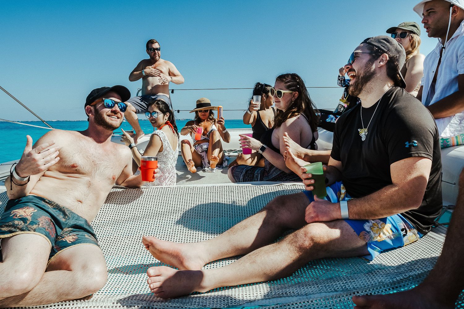 Friends relaxing on boat cushions during a sailing trip in bright sunshine.