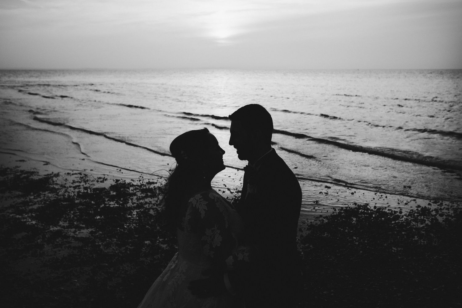 Silhouette of a couple embracing against a sunset beach backdrop.