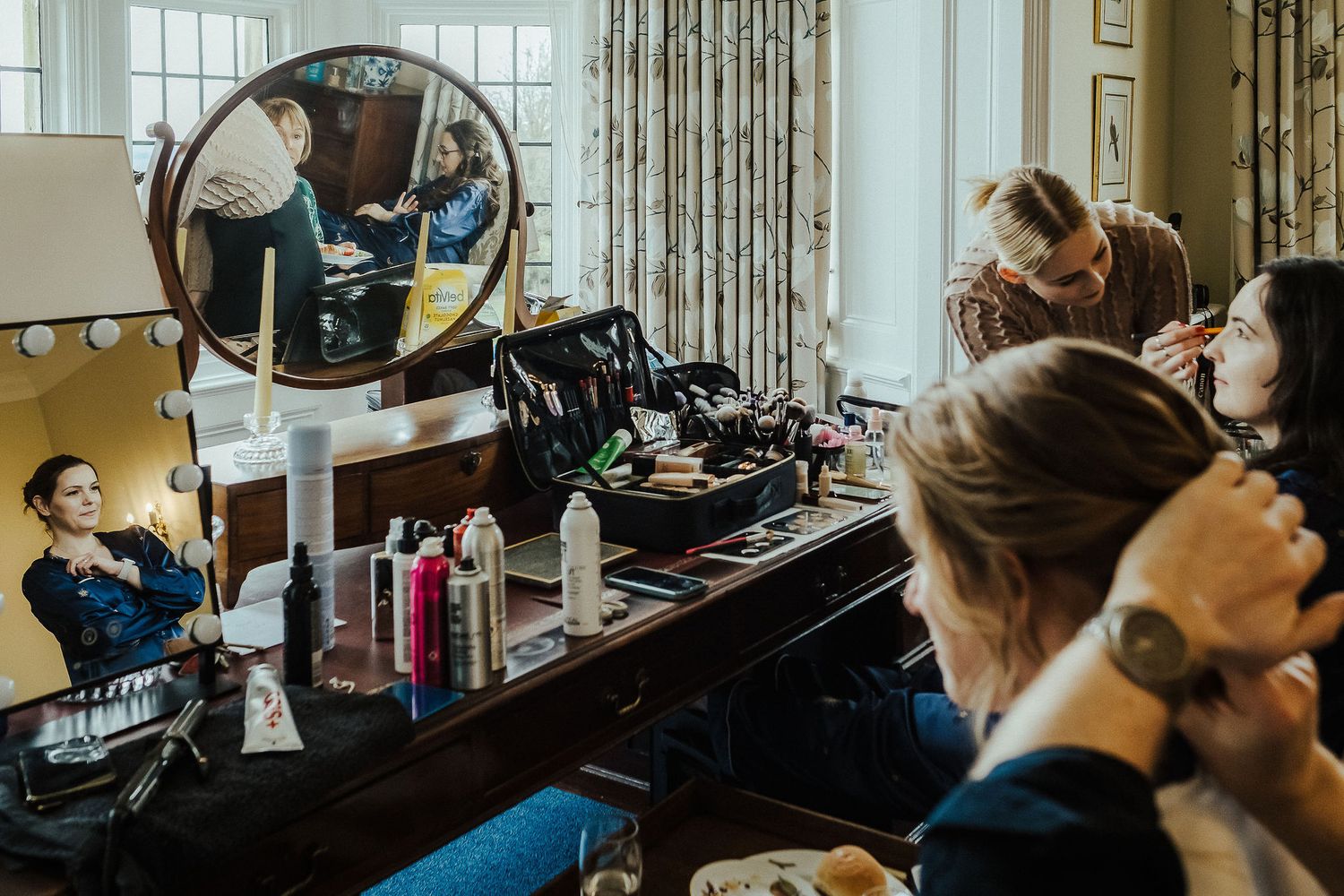 Preparation scene in a brightly lit dressing room with mirrors and styling products.
