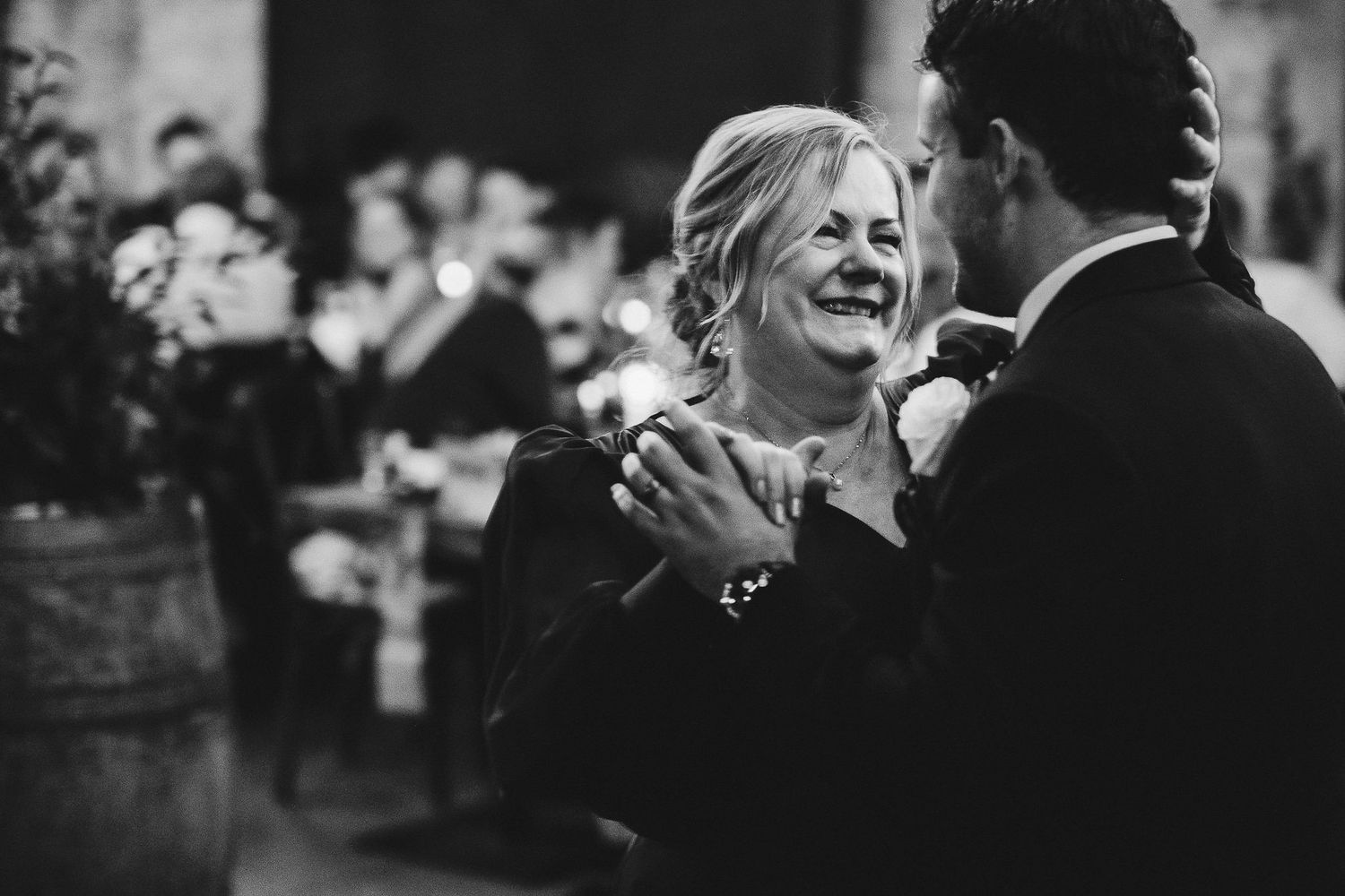 A black and white photograph capturing a heartfelt moment of shared laughter at a celebration.