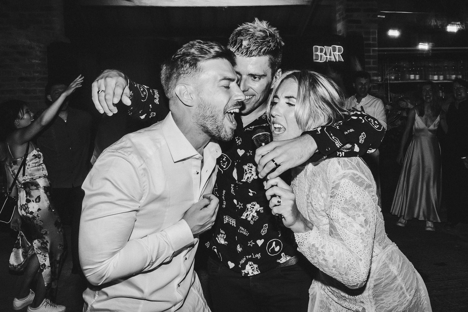 Wedding guests share a fun candid moment singing together at the reception party.