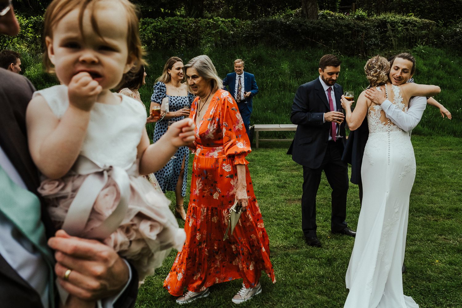 Wedding celebration with guests dancing and enjoying festivities on a grassy lawn.