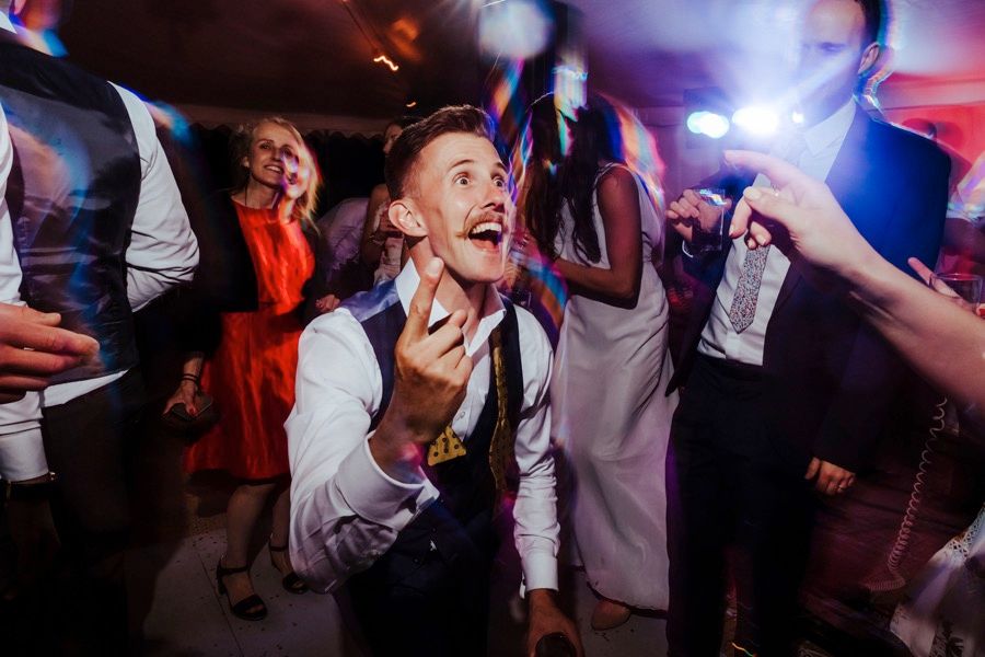 Wedding reception dance party with vibrant red and blue lighting creating an energetic atmosphere.