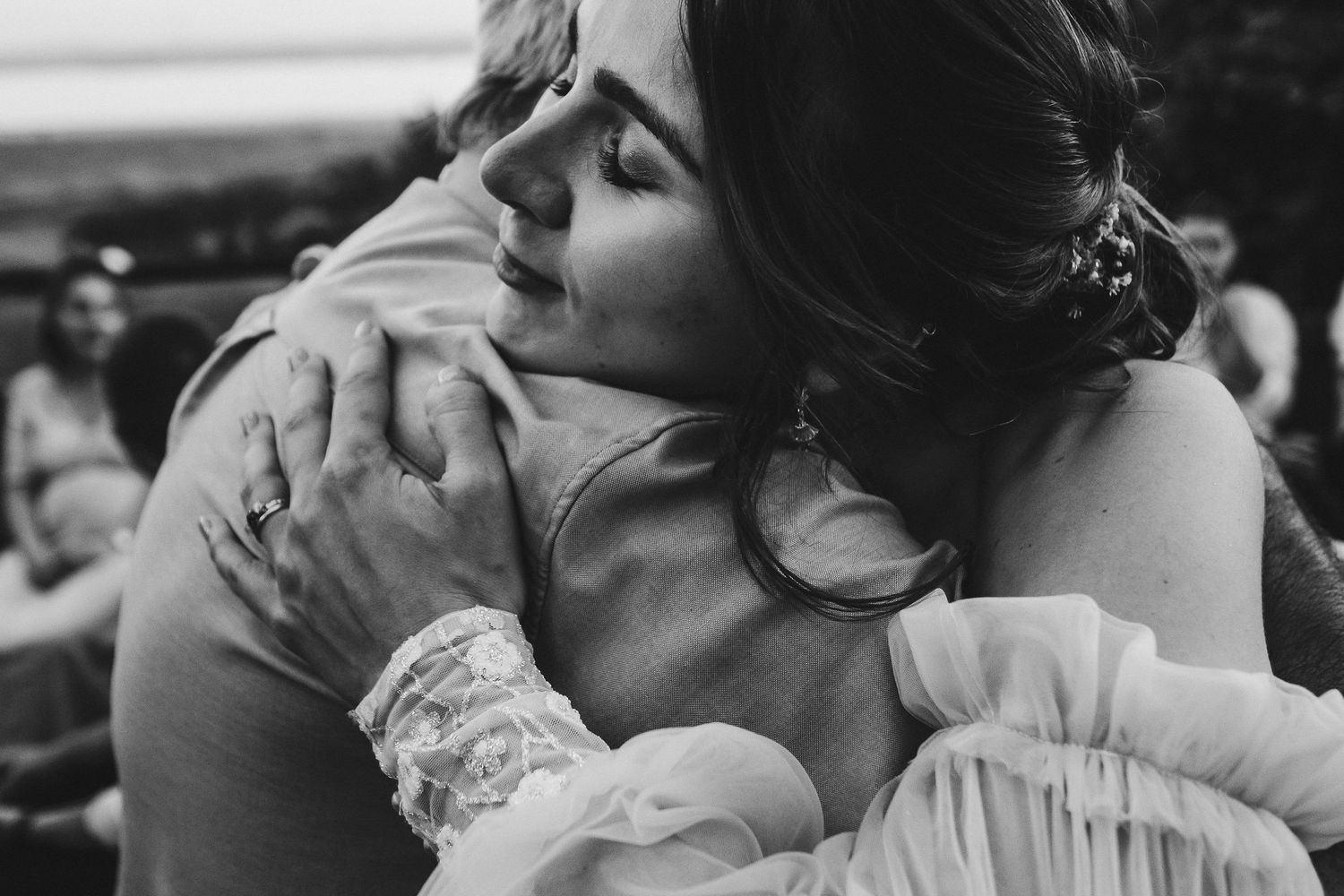 Emotional black and white photograph captures intimate embrace at wedding celebration.