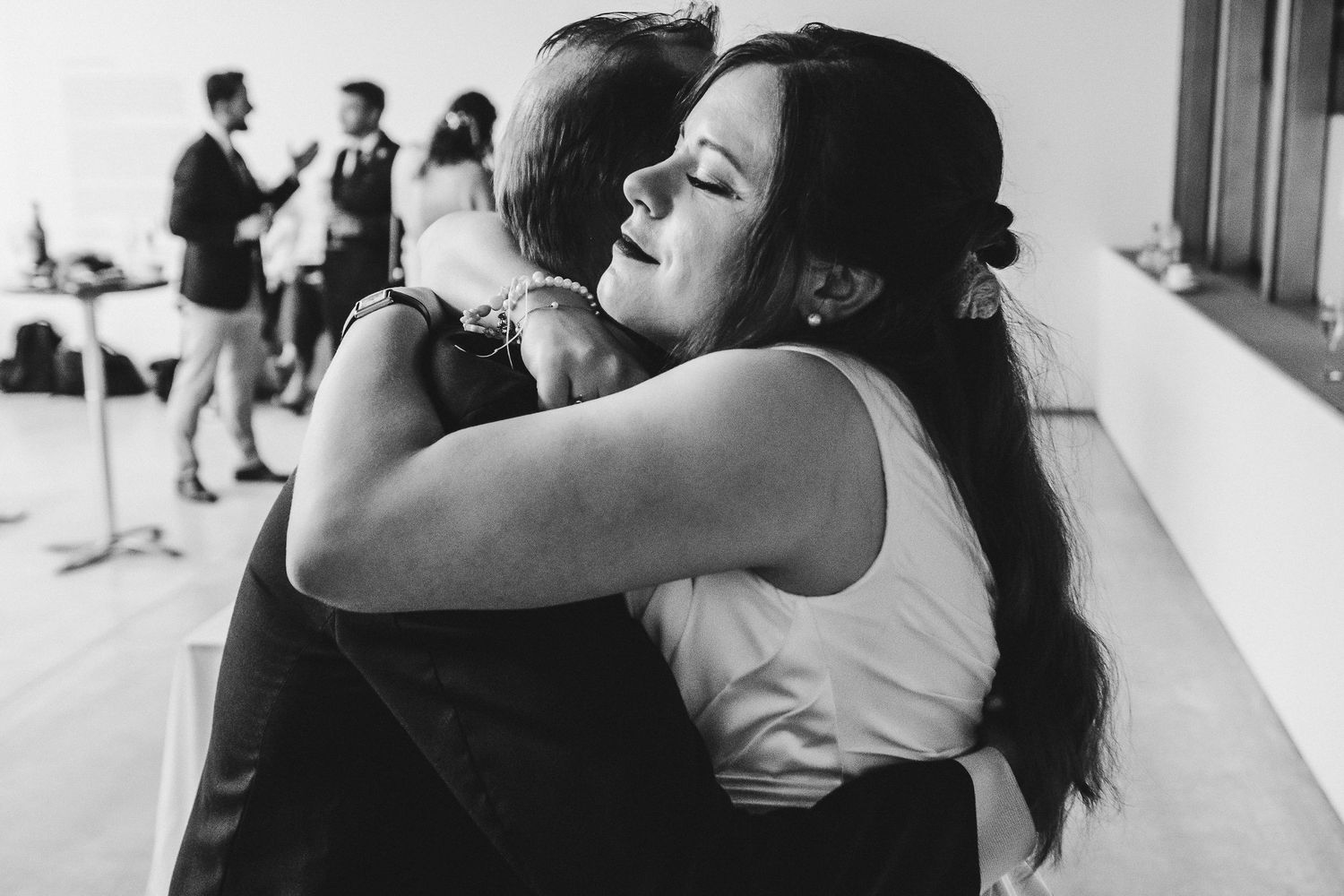 An intimate black and white capture of an emotional hug at a wedding celebration.