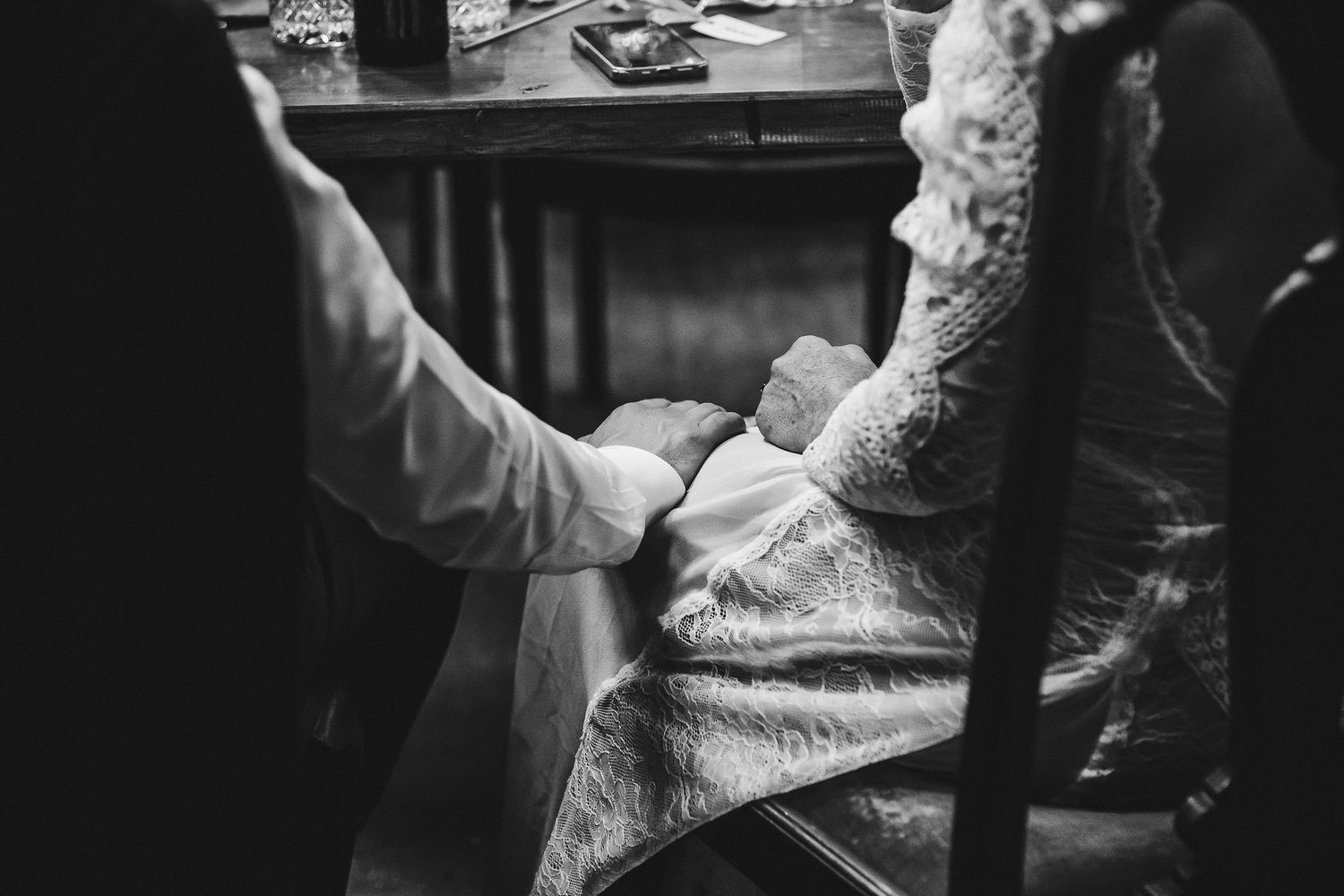 Black and white photo shows tender moment during wedding reception.