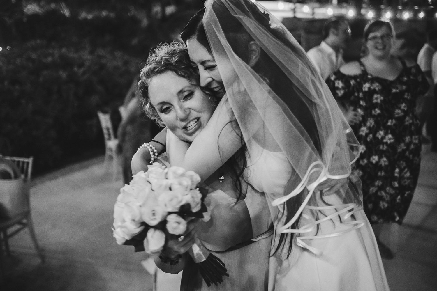 An emotional embrace during a wedding celebration with a white bouquet.