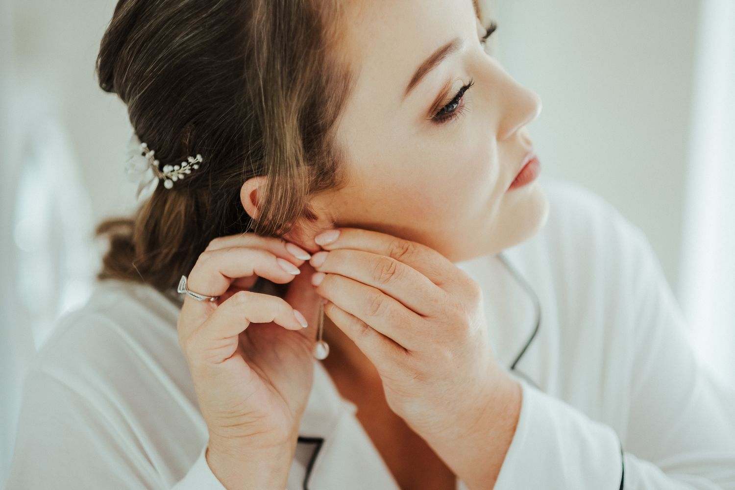Putting on jewelry and final touches during wedding preparation.
