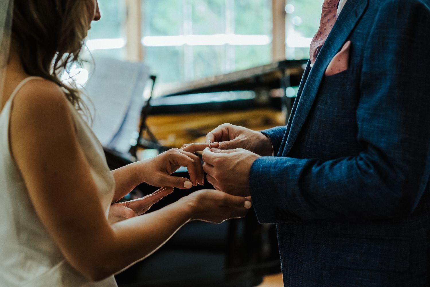 Close-up shot of hands exchanging rings during an intimate wedding ceremony.