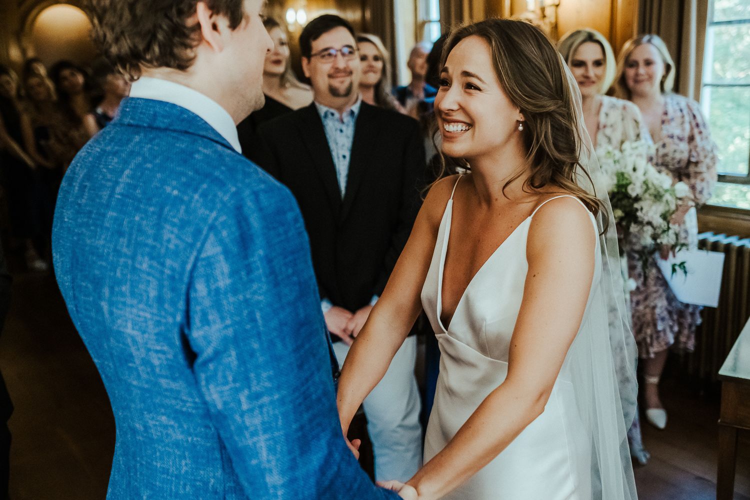 Intimate indoor wedding ceremony with natural light streaming through windows.