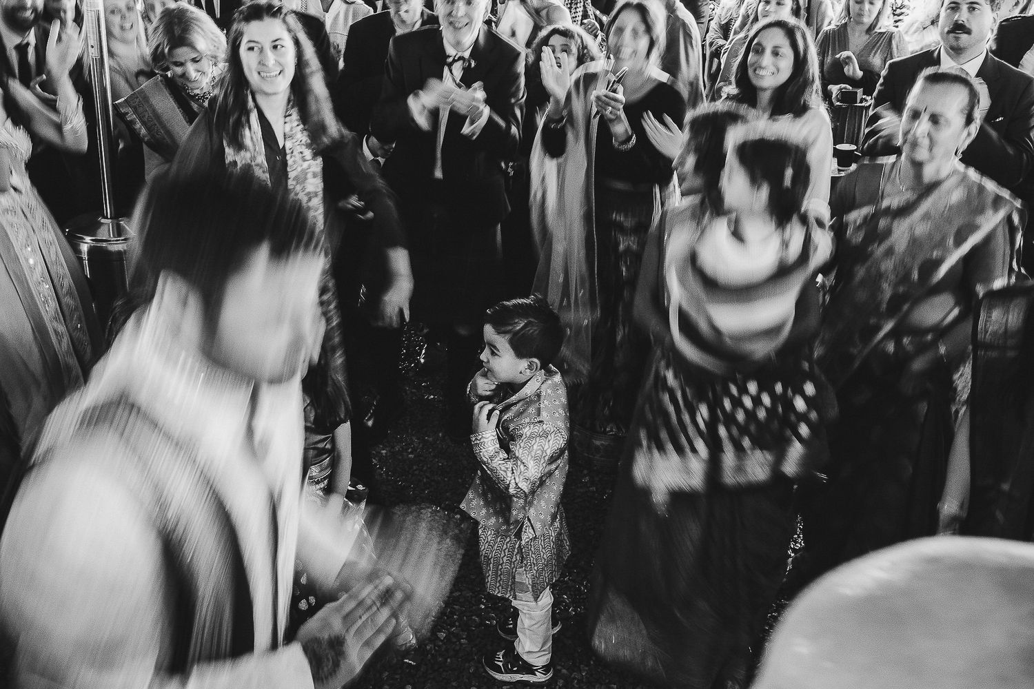 Blurred motion captures energetic dancing at dimly lit wedding reception.
