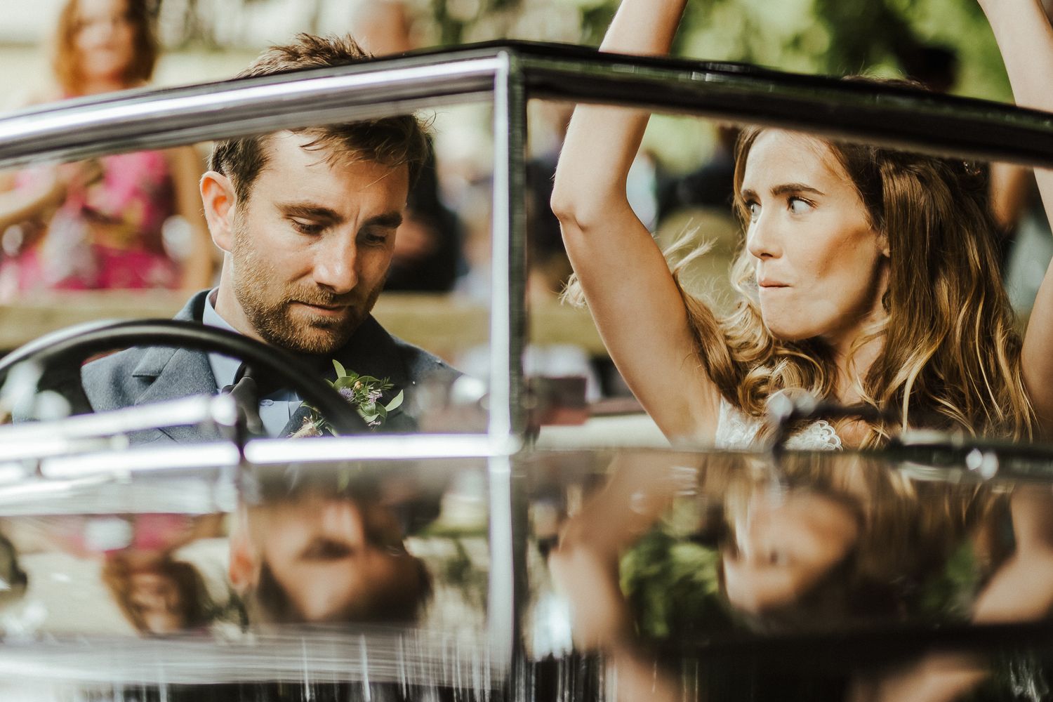 Artistic reflection shot of newlyweds through a car window.