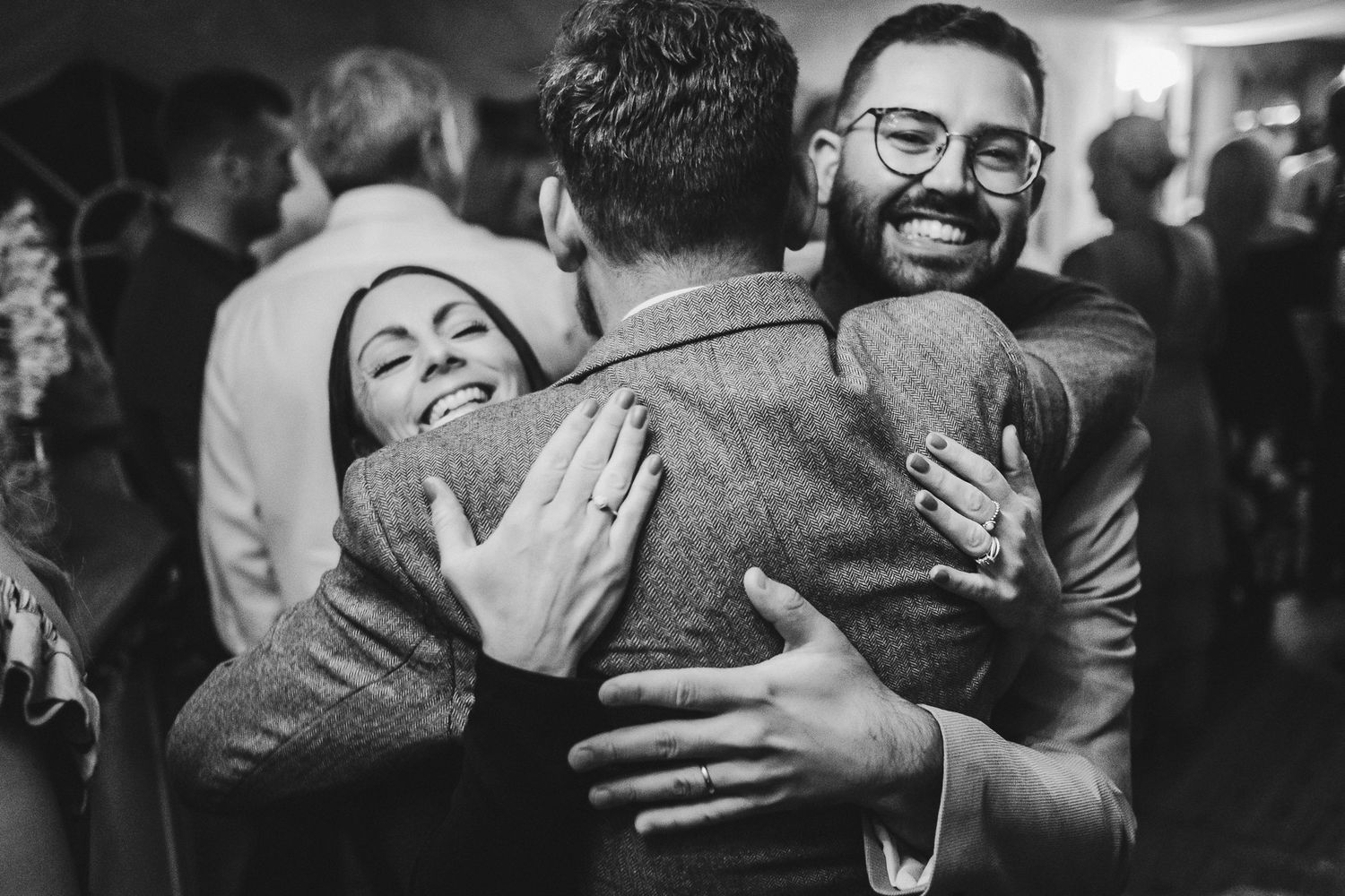 Joyful group embrace captured in black and white at celebration event.