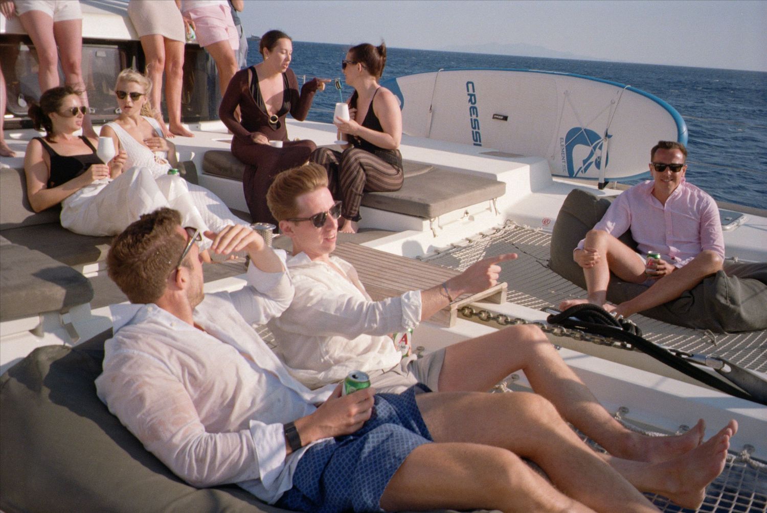 A group of people relaxing and socializing on the deck of a boat during a sunny day at sea.