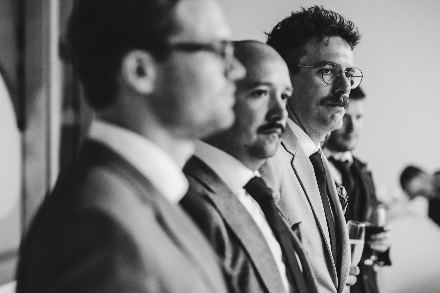 Black and white portrait series of groomsmen lined up at a wedding ceremony.