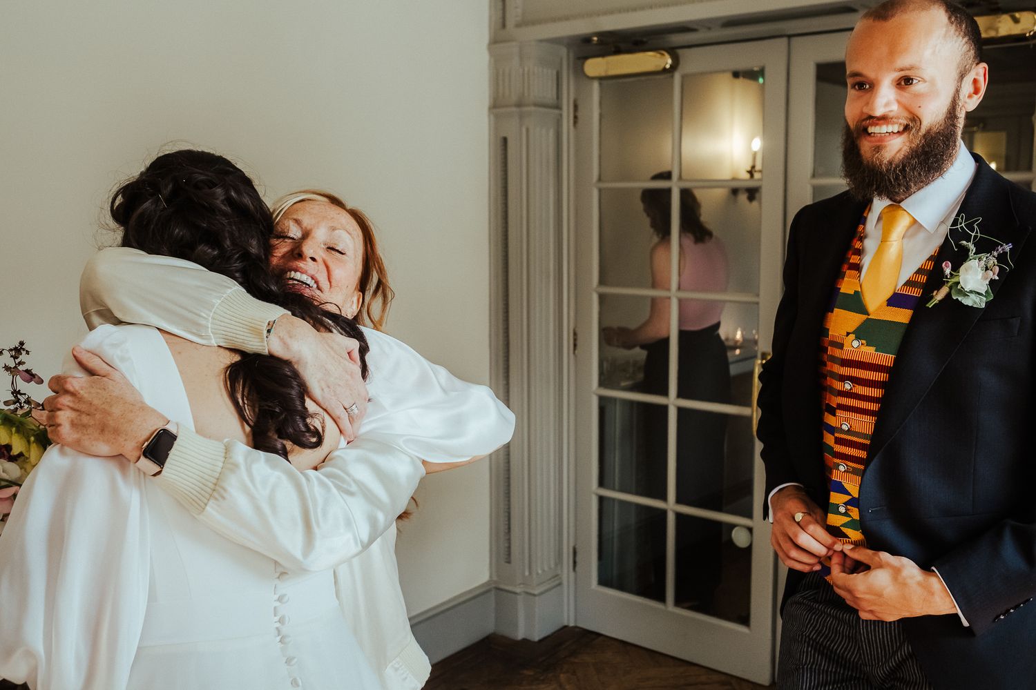 Warm celebratory embrace at indoor wedding reception.