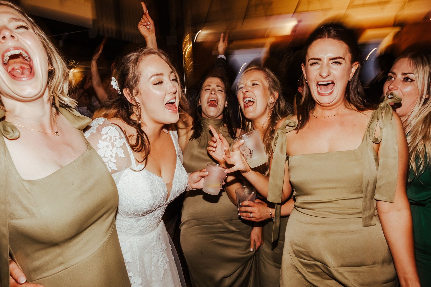 Candid moment of wedding guests singing and celebrating with enthusiastic expressions.