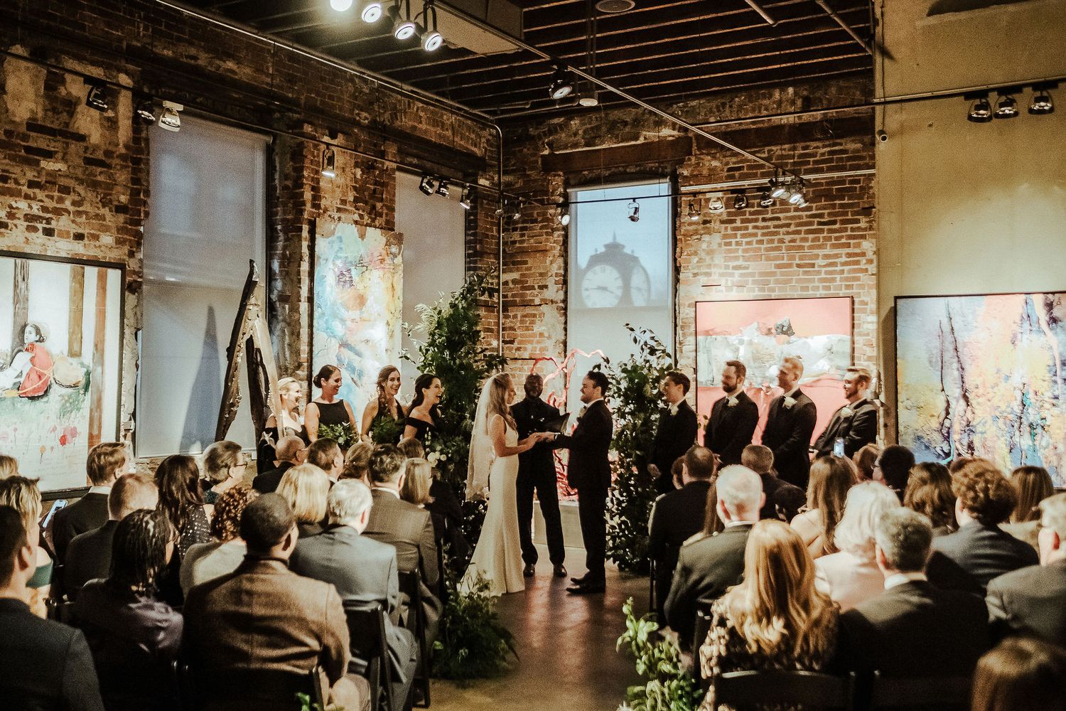 Wedding ceremony in industrial venue with exposed brick walls and natural decorations.