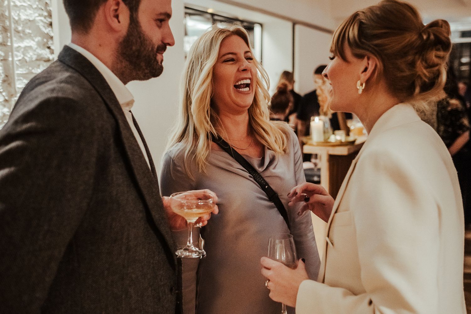 Friends share laughter while enjoying drinks at an elegant indoor gathering.