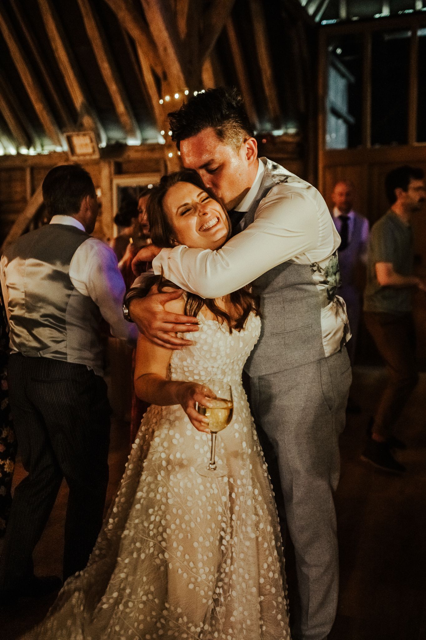 A tender dance moment between newlyweds in a rustic barn venue.