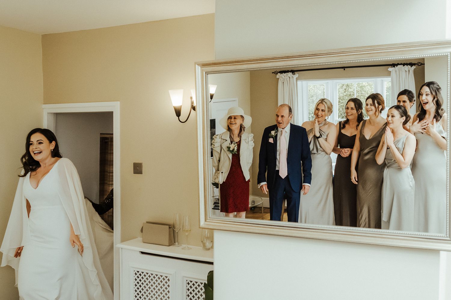 Mirror reflection shows wedding party members watching and reacting with emotion.