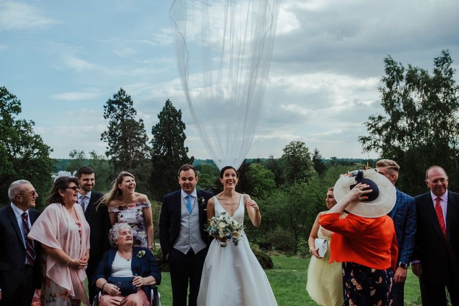 Wedding guests gather outdoors on a hilltop under power lines during a countryside celebration.