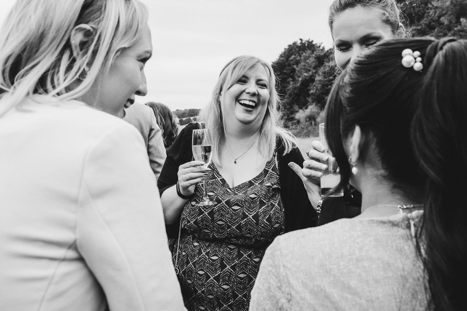 Black and white wedding photos show joyful candid moments between a couple and their guests celebrating outdoors.