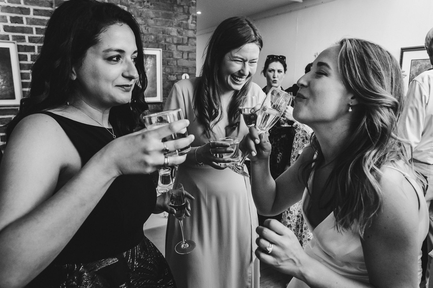 Black and white photo of friends sharing drinks and conversation at a party.