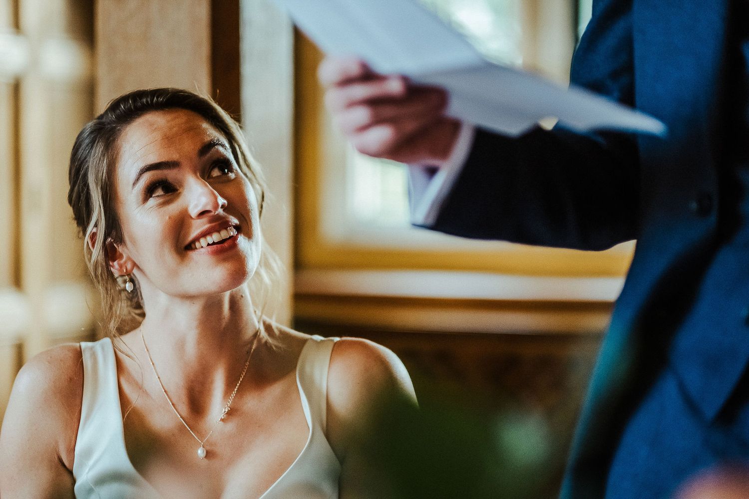 Candid emotional reactions during wedding reception in warm-lit indoor venue.