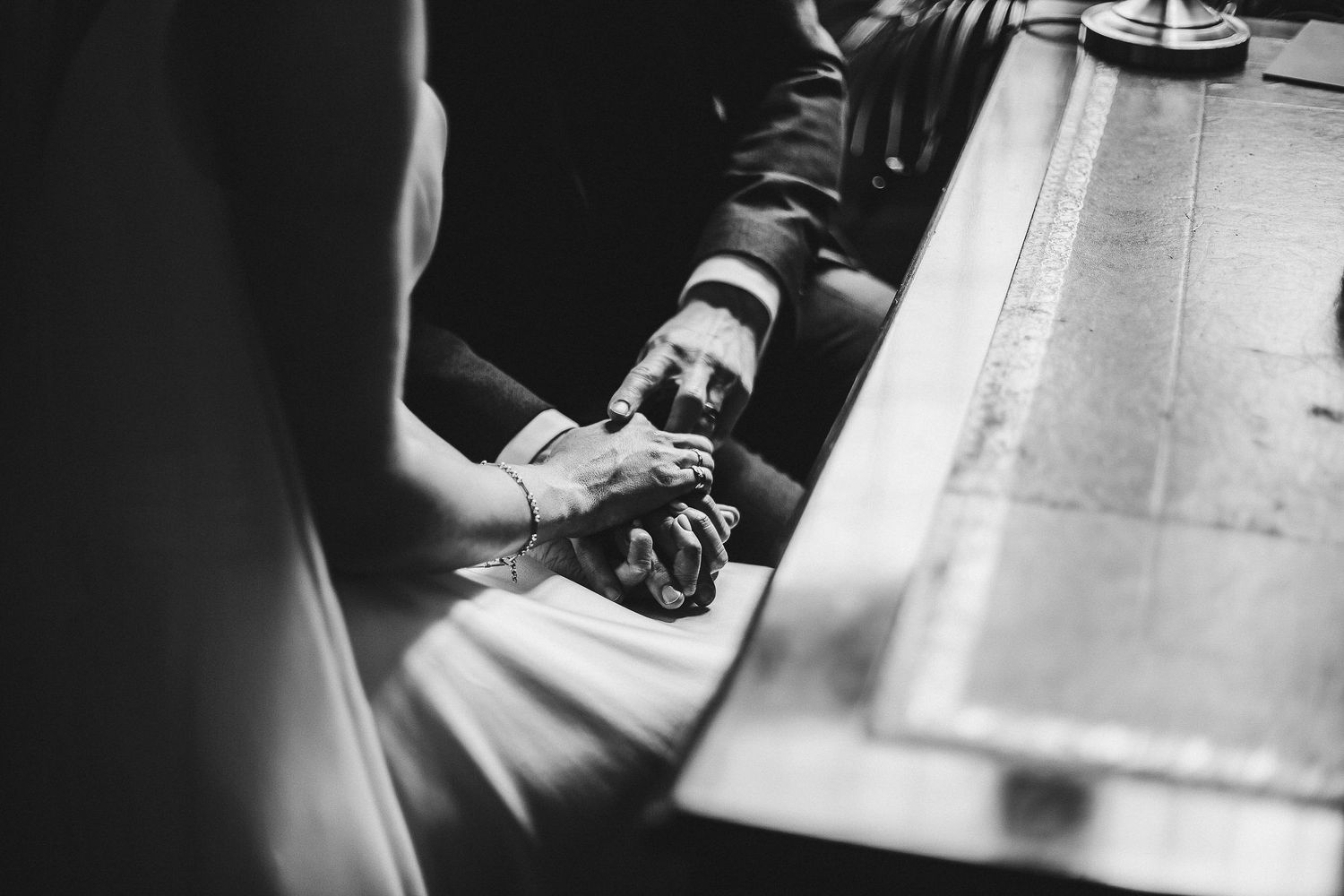 Close-up black and white shot of hands signing wedding documents.