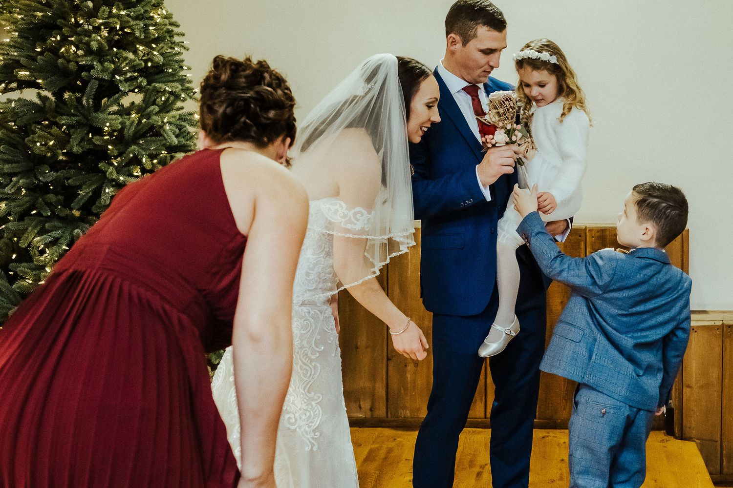 Wedding party interacts with children during indoor celebration.