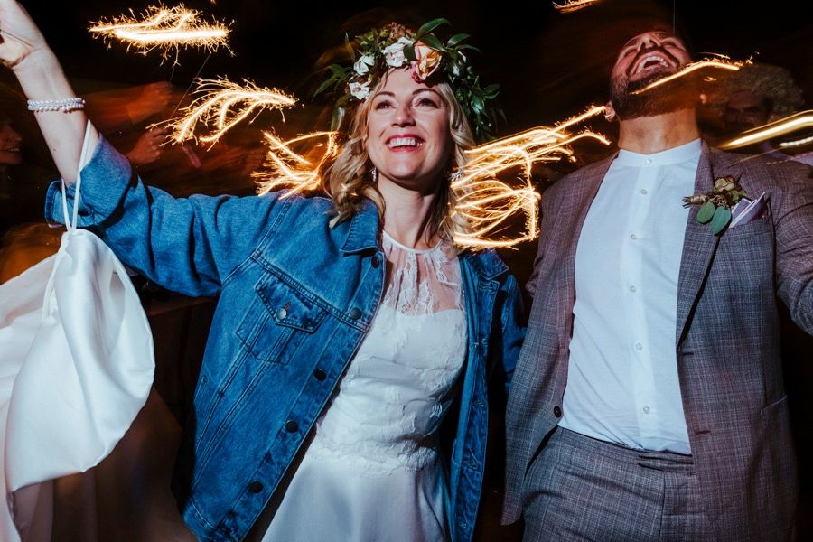 Wedding reception guests dancing with sparklers creating light trails.