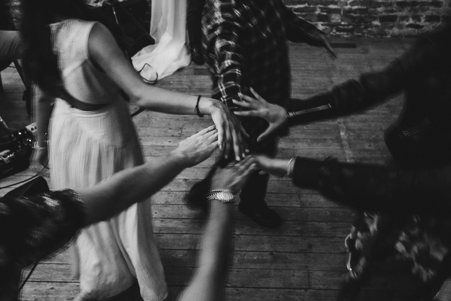 Black and white shot of people dancing at a wedding reception with dramatic lighting.