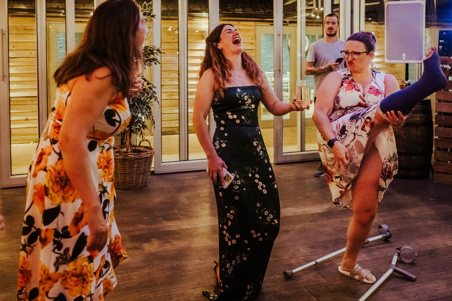 Guests in colorful floral dresses dance and celebrate at a wedding reception.