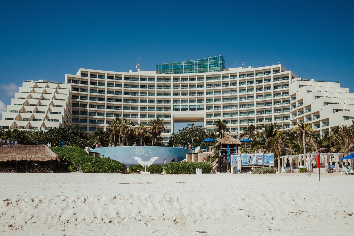 Modern curved resort hotel building with pool and beach access in Cancun.