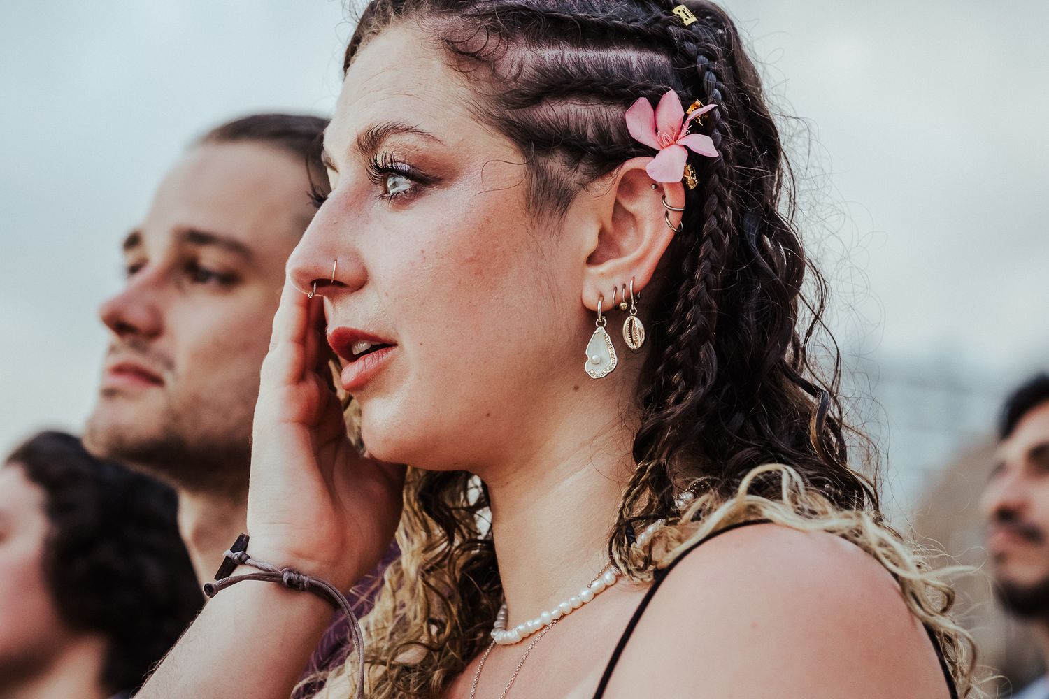 Wedding guest with braided hair and flower accessory showing emotion during ceremony.