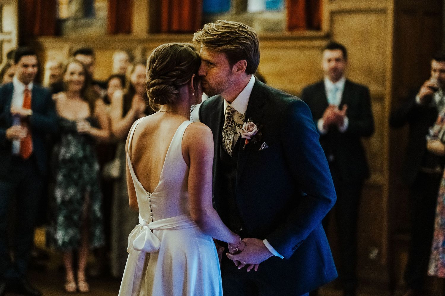 A romantic moment between newlyweds during their first dance in an elegant wood-paneled venue.